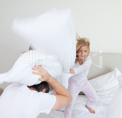 Girl hitting her father with pillow