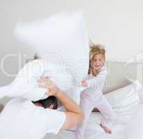 Girl hitting her father with pillow