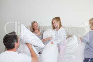 Family having a pillow fight in the bedroom