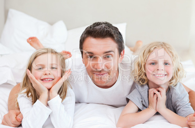 Father lying on the bed with his children