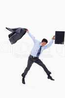 Businessman jumping while holding his jacket and a briefcase