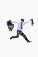 Cheerful businessman jumping while holding his jacket and a brie
