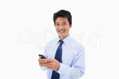 Smiling businessman sending a text message