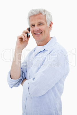 Portrait of a smiling man making a phone call while looking at t