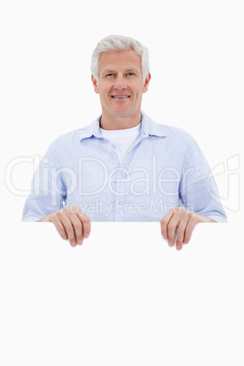 Portrait of a mature man standing behind blank board