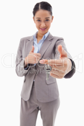 Portrait of a businesswoman holding a key with the thumb up