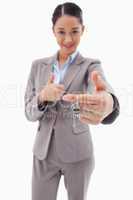 Portrait of a businesswoman holding a key with the thumb up