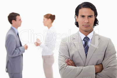 Serious businessman with talking colleagues behind him