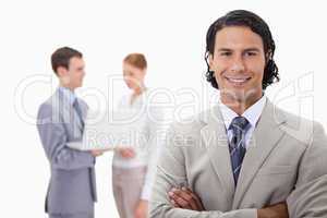 Smiling businessman with colleagues working on laptop behind him