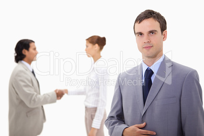 Businessman with hand shaking colleagues behind him