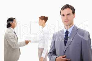 Businessman with hand shaking colleagues behind him