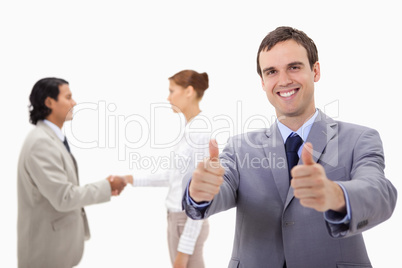 Businessman approving with hand shaking colleagues behind him