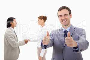 Businessman approving with hand shaking colleagues behind him