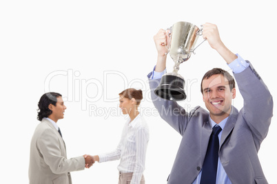 Businessman raising cup with hand shaking colleagues behind him