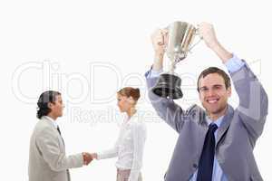 Businessman raising cup with hand shaking colleagues behind him