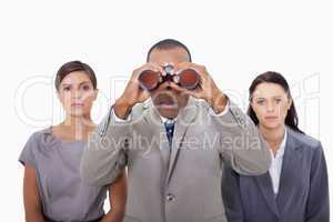 Businessman with colleagues using binoculars