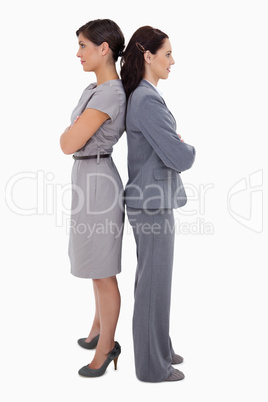 Businesswomen with arms folded standing back on back