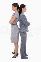 Businesswomen with arms folded standing back on back