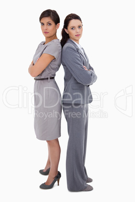 Serious businesswomen standing back on back