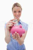 Money being put into piggy bank by woman