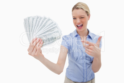 Woman holding money and pointing at it