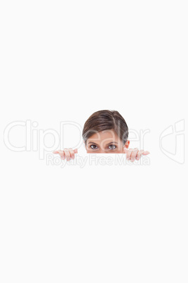 Sneaky woman looking over blank wall