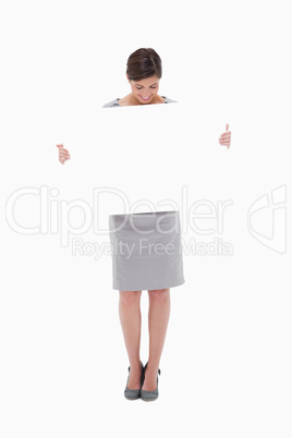 Woman looking down at blank sign in her hands