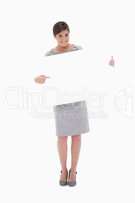 Smiling woman pointing at blank sign in her hands