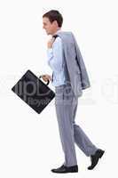 Side view of walking and smiling businessman with suitcase
