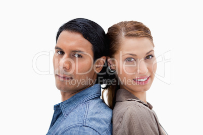 Side view of young couple standing back to back