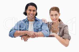 Couple leaning on blank wall