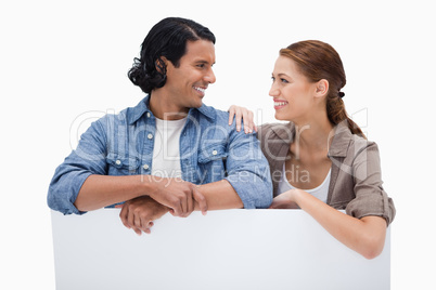 Smiling couple leaning on blank wall