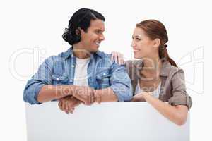 Smiling couple leaning on blank wall