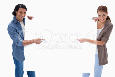 Smiling couple pointing at blank sign in their hands