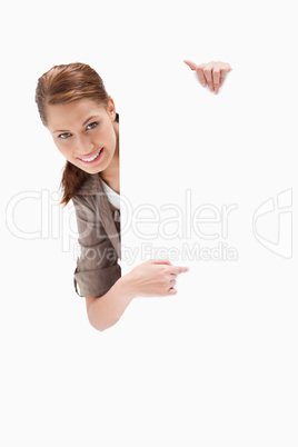 Smiling woman pointing around blank sign