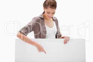 Woman pointing down at blank signboard