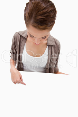 Woman pointing down at blank signboard in her hand