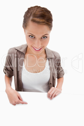 Smiling woman pointing down at blank signboard