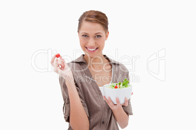Woman with bowl of salad and small tomato in her fingers