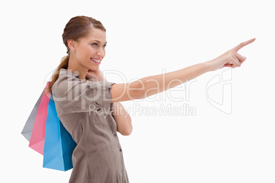 Side view of pointing woman with shopping bags