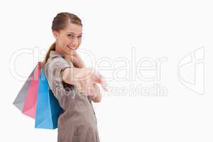 Side view of smiling woman pointing with shopping bags