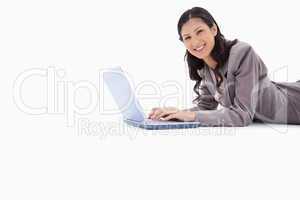 Side view of smiling woman lying while working on laptop