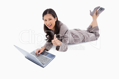 Lying woman with laptop giving thumb up