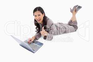 Lying woman with laptop giving thumb up