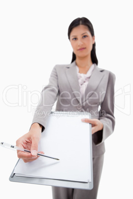 Clipboard and pen being handed over by businesswoman
