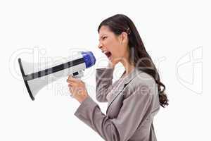 Side view of angry businesswoman yelling through megaphone