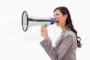 Side view of angry businesswoman shouting through megaphone