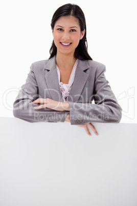 Smiling young businesswoman leaning on blank wall