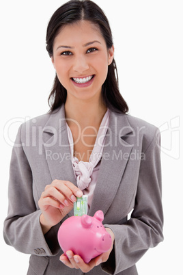 Businesswoman putting money into piggy bank