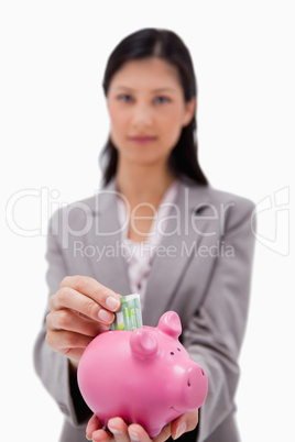 Money being put into piggy bank by businesswoman